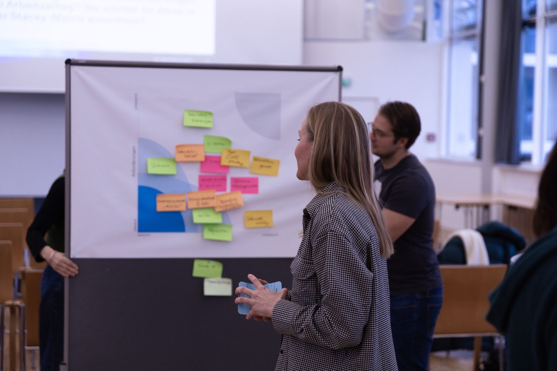Eine Mitarbeiterin der byte steht mit dem Rücken zum Publikum vor einer Pinnwand mit Post Its